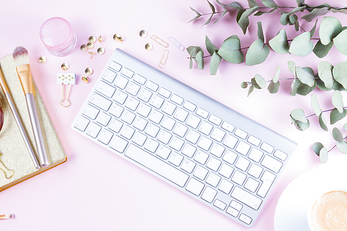 Flat lay home office workspace - white modern keyboard with female accessories on pink background