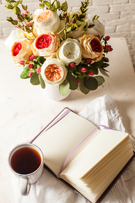 a cup of 홍차, notebook and beautiful flowers on the table. morning inspiration for the day planning