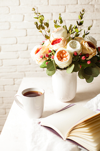 a cup of 홍차, notebook and beautiful flowers on the table. morning inspiration for the day planning