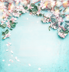 Beautiful spring nature background with lovely blossom, petal and bokeh on turquoise blue background , top view, frame. Springtime concept