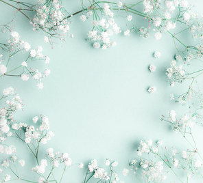 Floral composition with light, airy masses of small white flowers on turquoise blue background, top view, frame.  Gypsophila Baby's-breath flowers