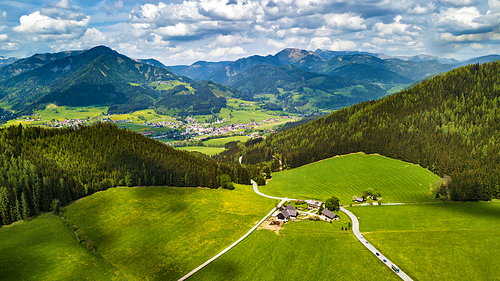 Spring travel in Austria. Green fields and meadows in Alps mountains. Road in alpine countryside.