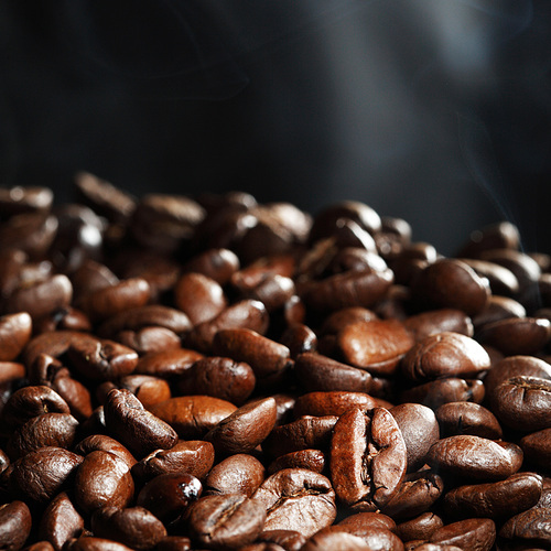 Hot roasted coffee beans and steam on black