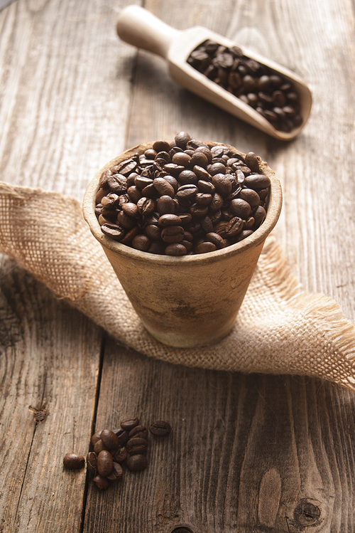 coffee beans in a clay pot on wooden background