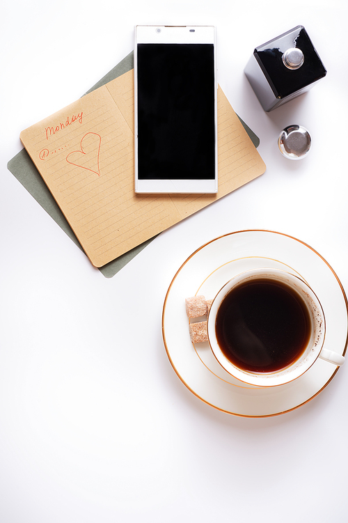 cup of coffee with diary and smartphone  around white background. flat lay