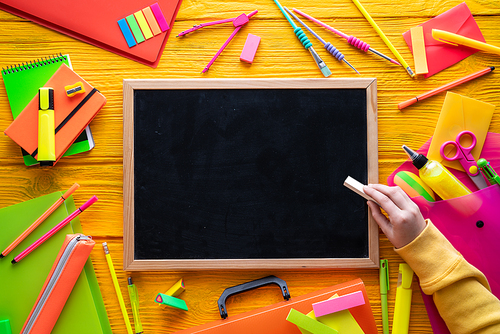 Back to school supplies arrangement vivid colorful neon color and blackboard hand chalk