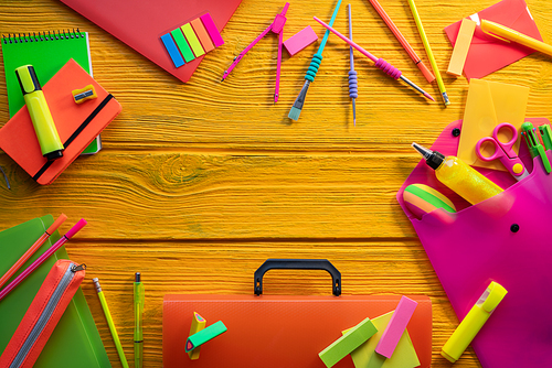 Back to school supplies arrangement vivid colorful neon color in yellow background desk