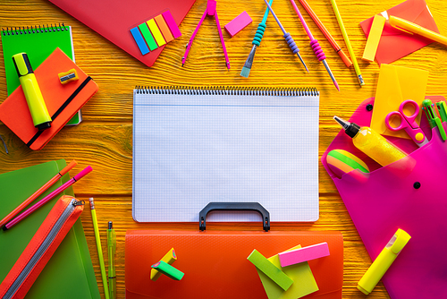 Back to school supplies arrangement vivid colorful neon color in yellow desk notebook