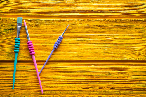 Back to school supplies colorful brushes on yellow desk