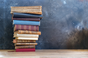 Stack of multicolored books on boockshelf, education, reading, back to school concept, copy space on blackboard