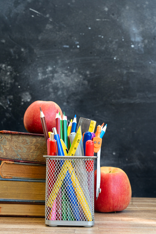 Back to school concept, school supplies with books and apples on blackboard background with copy space