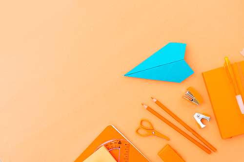 Back to school styled border with school supplies and paper blue plane orange background