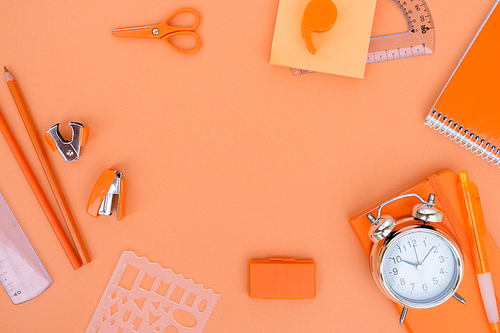 Back to school styled flat lay frame scene with school supplies on orange background