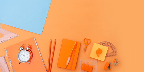 Back to school styled flat lay scene with school supplies on blue and orange background