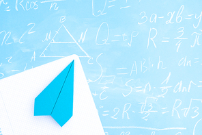 Back to school minimal flat lay styled scene with paper plane on blue background with math formulas