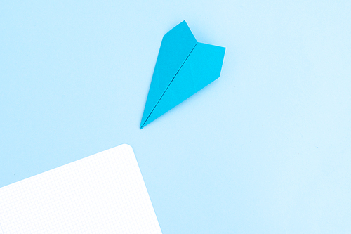 Back to school minimal flat lay styled scene with paper plane on blue background