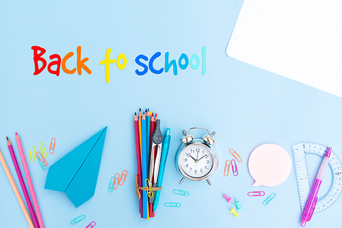 Back to school styled scene with school supplies on blue background with greeting
