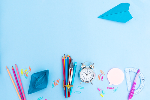 Back to school styled scene with school supplies and papercraft on blue background