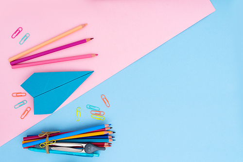 Back to school styled flat lay scene with school supplies on pink and blue background