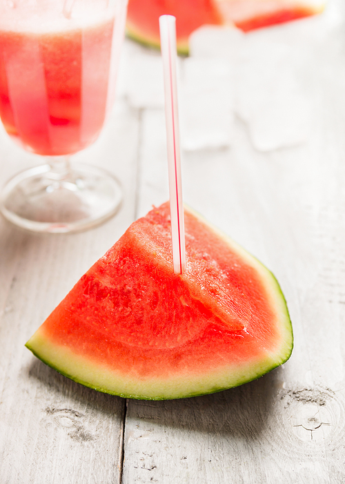 watermelon with drink straw on white wooden background, close up