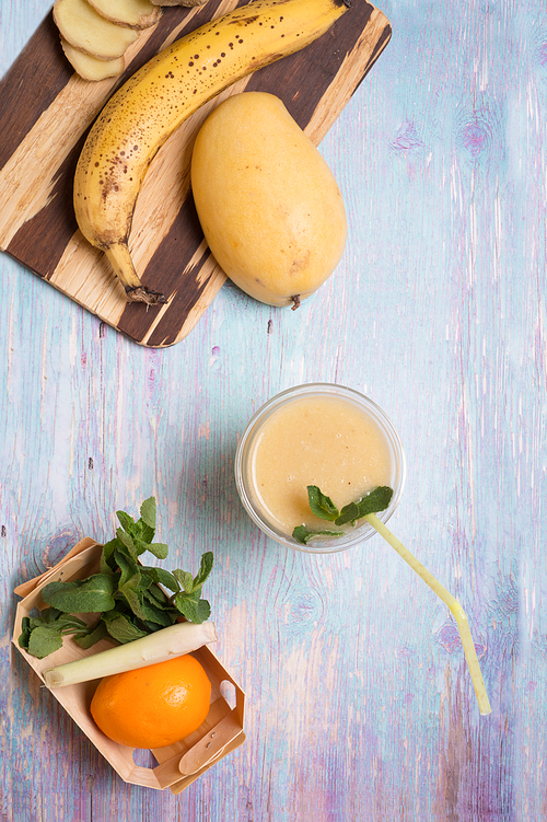 recepie of healthy fresh yellow fruit mango smoothie at blue table
