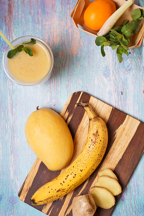 recepie of healthy fresh yellow fruit mango smoothie at blue table