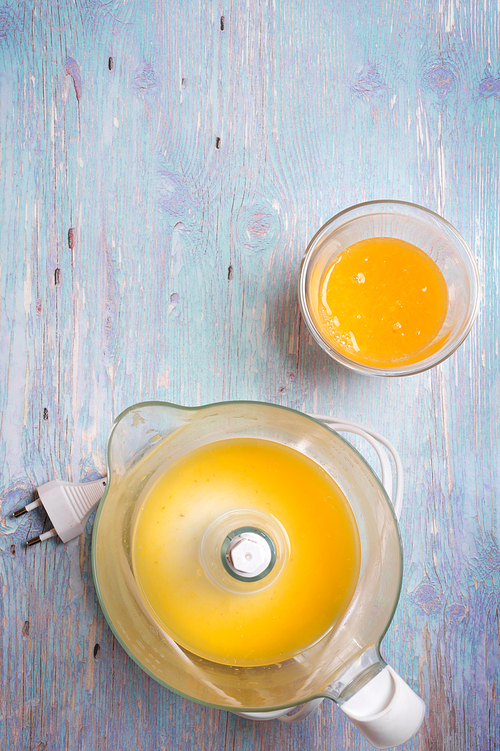 fresh orange juice with juicer at blue table