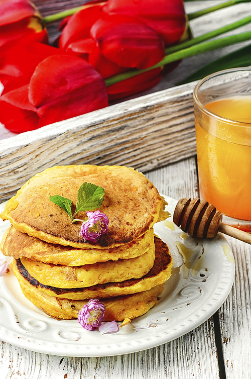 Pumpkin pancakes with glass of the juice and flowers to the morning breakfast