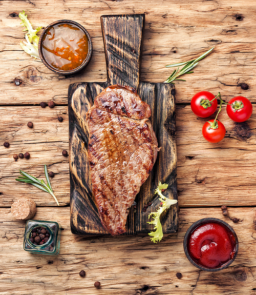 Grilled beef steaks with spices on wooden cutting board.Succulent grilled steak