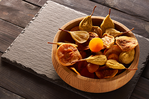 Dried fruits on slate plate over vintage rustic wooden background