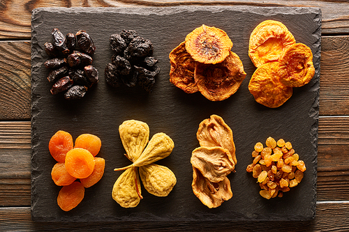 Dried fruits on slate plate over vintage rustic wooden background