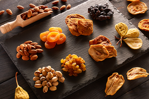 Dried fruits and nuts on slate plate over vintage rustic wooden background