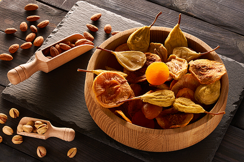 Dried fruits and nuts on slate plate over vintage rustic wooden background