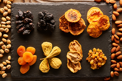 Dried fruits and nuts on slate plate over vintage rustic wooden background