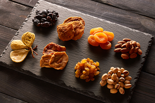 Dried fruits and nuts on slate plate over vintage rustic wooden background