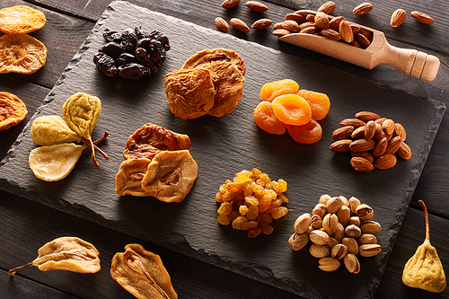 Dried fruits and nuts on slate plate over vintage rustic wooden background