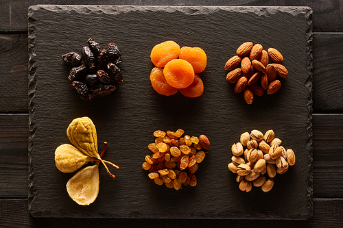 Dried fruits and nuts on slate plate over vintage rustic wooden background