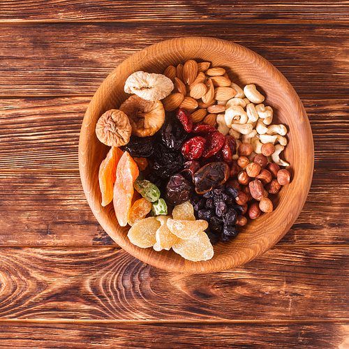 Dry fruits and nuts in bowl on wooden table. Copy space background - close up healthy sweets