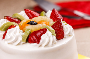 A close up of a white cake topped with various fruits.