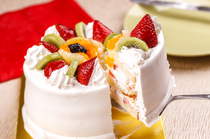 Lifting a slice of white cake topped with fresh fruit.