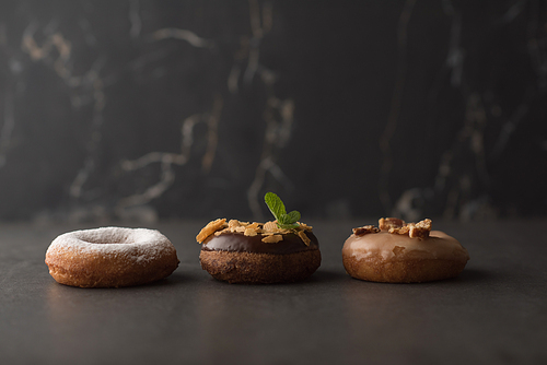 Three donuts on dark stone background
