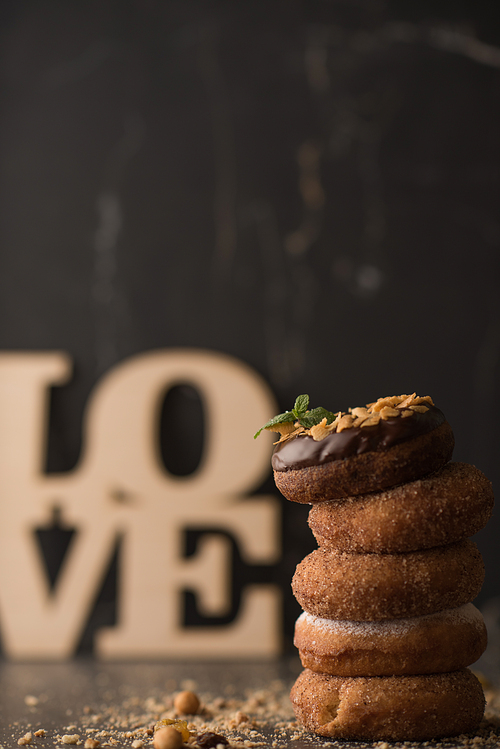 Stack of Donuts with crumbs, nuts and love sign on dark stone background