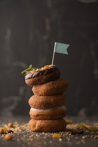 Stack of Donuts with crumbs, nuts and flag on dark stone background