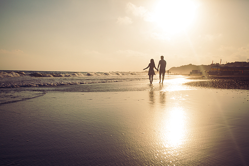 Silhouette of loving couple that walking along a sandy beach and enjoying sunset