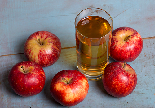 Glass of apple juice and a red apples on a blue old wooden background