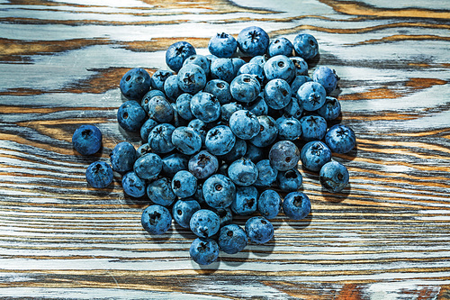 Heap of blueberries on wooden board.