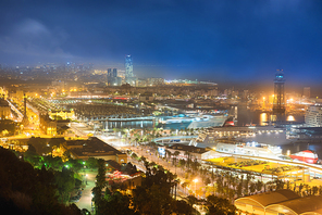 City of Barcelona at night. View on port and cityscape with blue dark sky