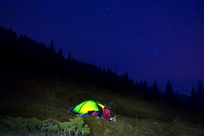 Illuminated orange camping tent under stars at night