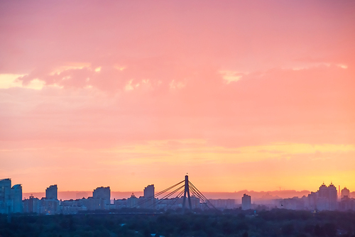 Modern cityscape with bridge and skyscrapers against beautiful colourful sunset