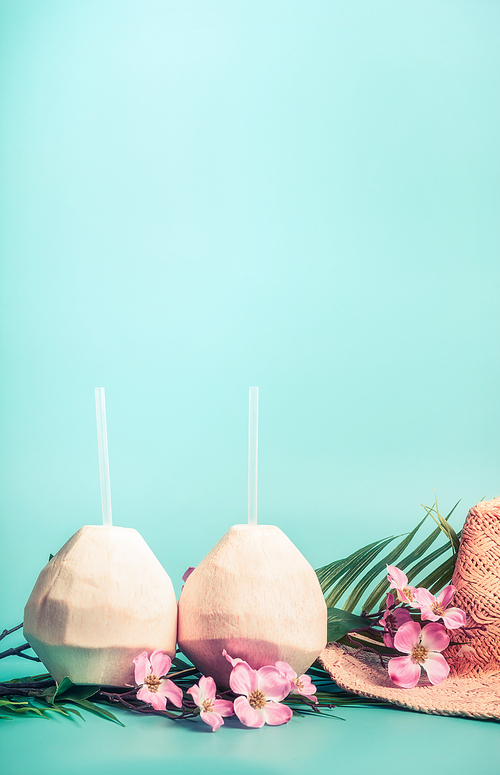 Summer holiday background with  coconut drinks,  straw hat, sunglasses. palm leaves and exotic flowers , front view. Tropical and beach vacation concept